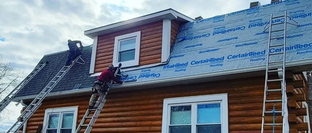 Roofers installing roof flashing and waterproof underlayment around dormer during roof replacement project